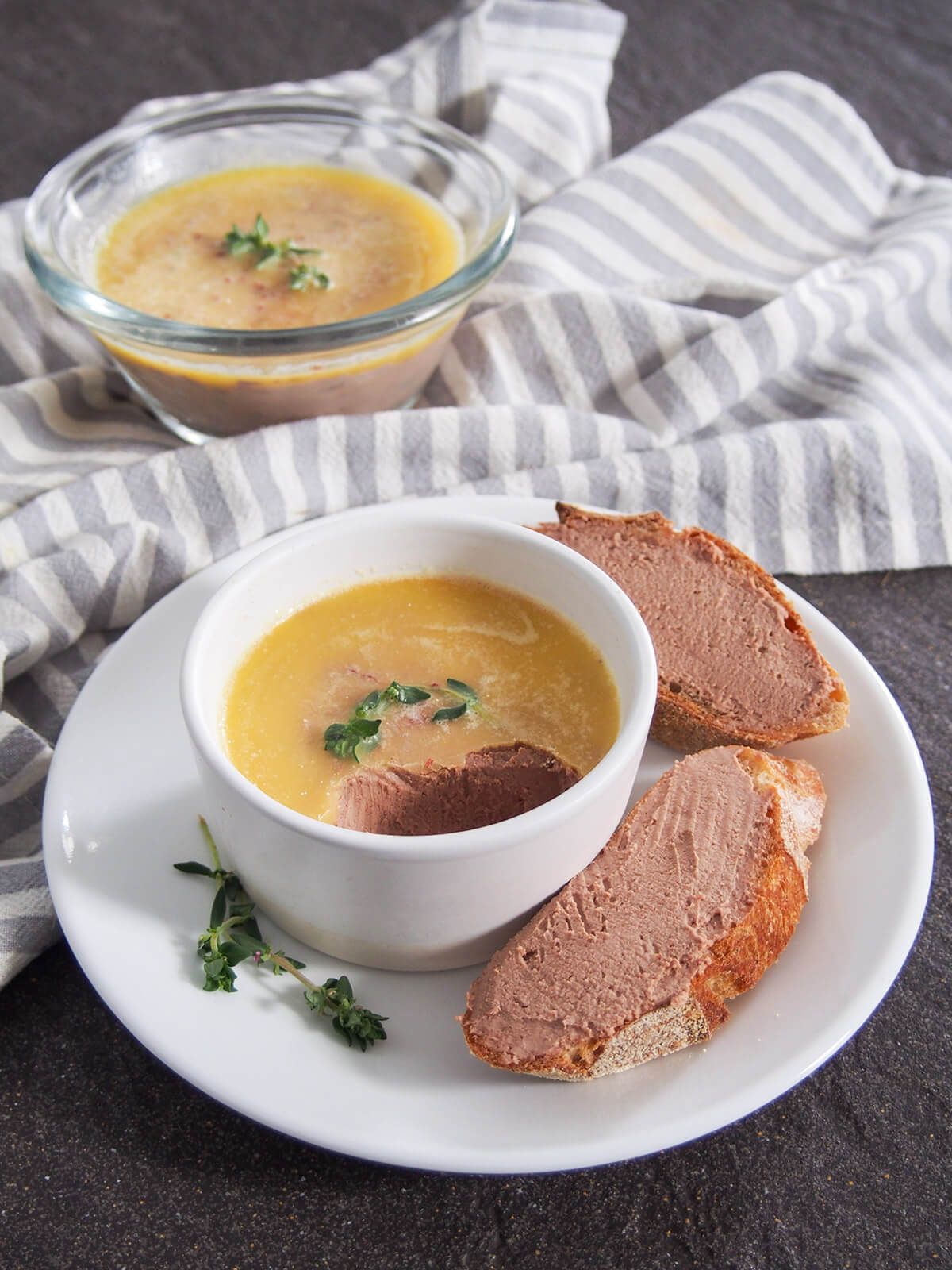 chicken liver pate in dish with some spread on bread to side and second dish with pate behind on cloth