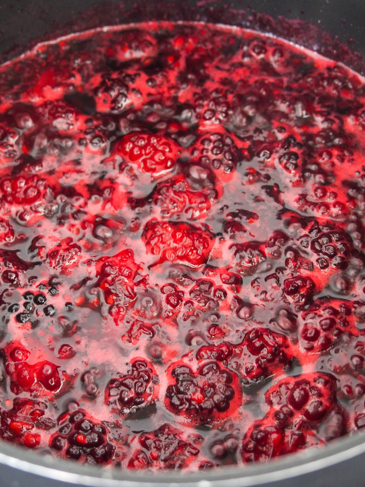 jam bubbling in pan showing chunks of berries