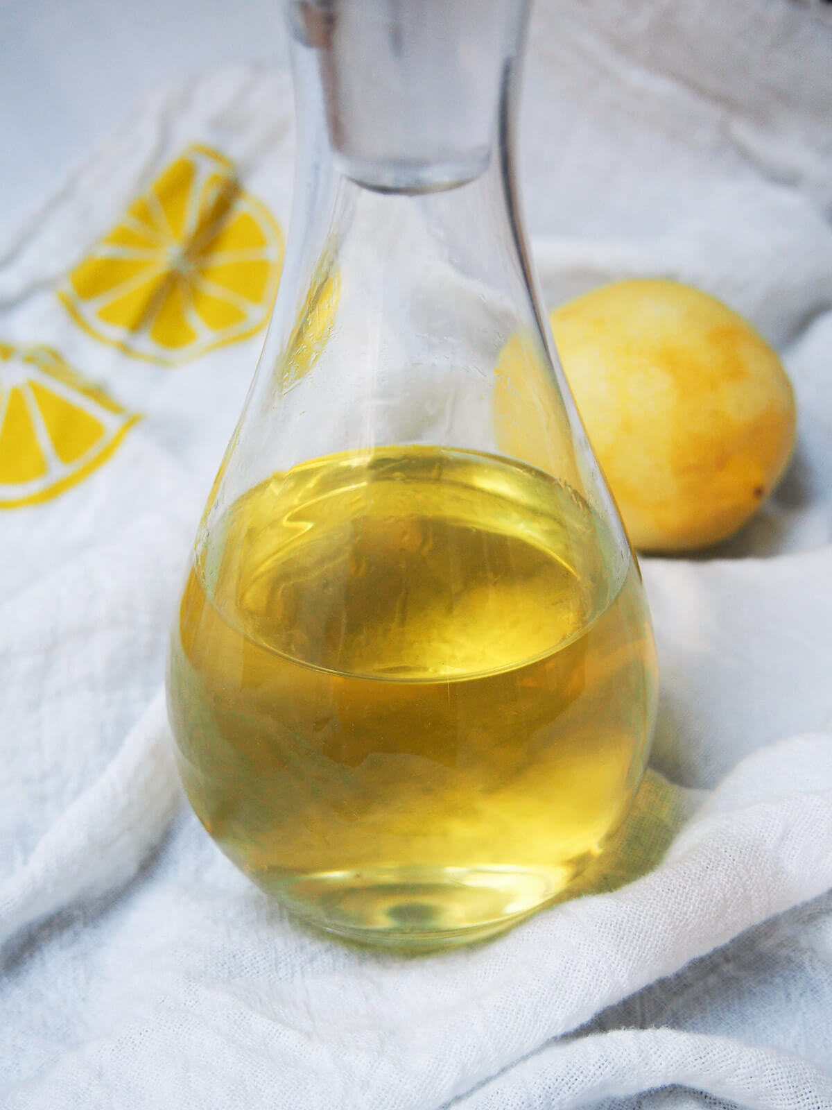 close view of homemade limoncello in bottle with lemon behind