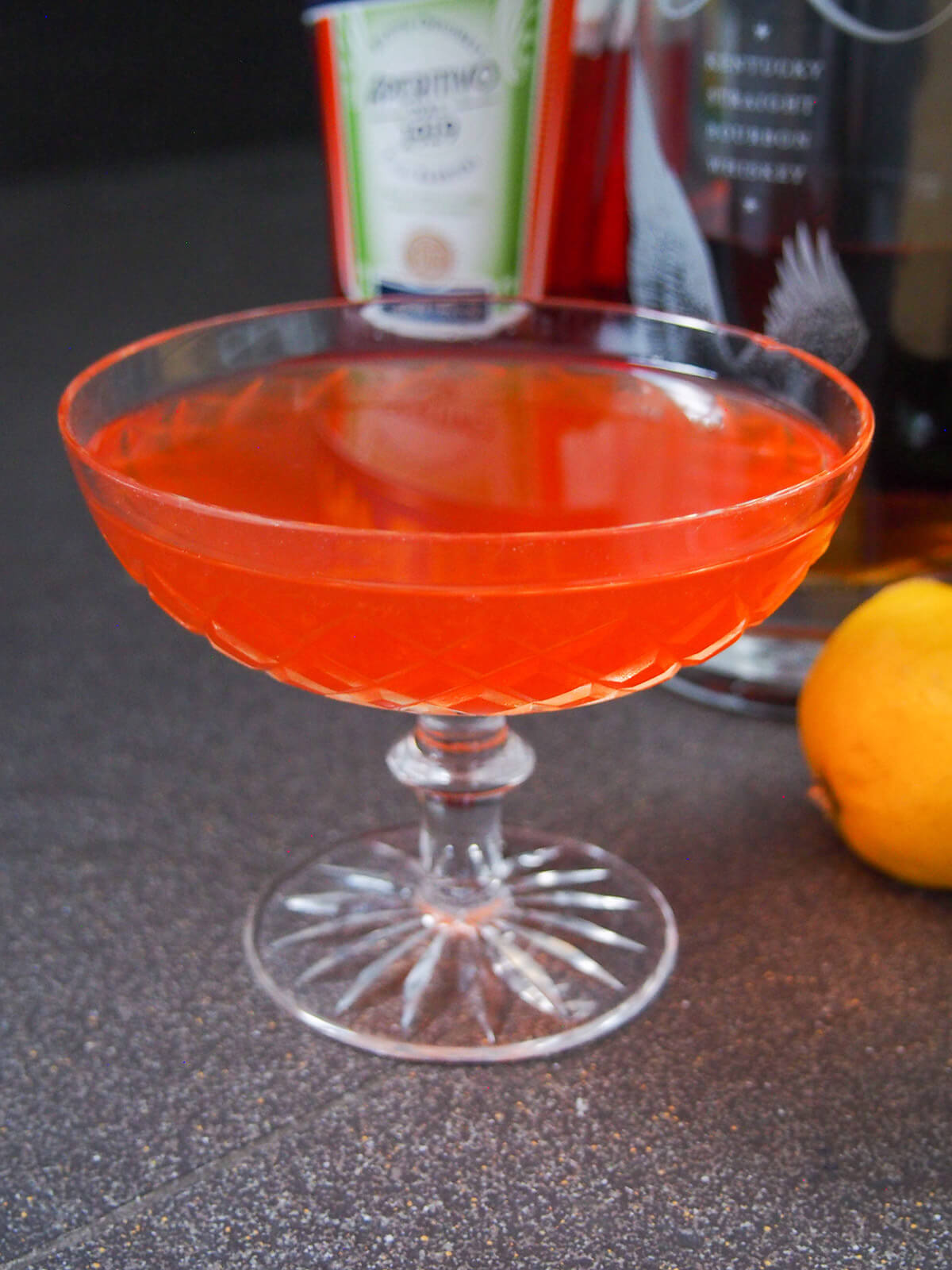 glass of paper plane cocktail with bottles behind