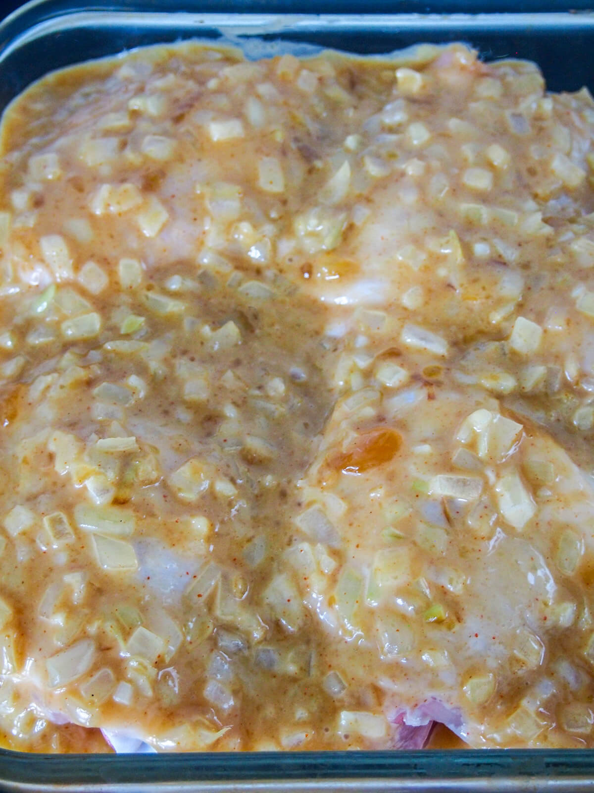 prepared chicken with sauce over top before cooking