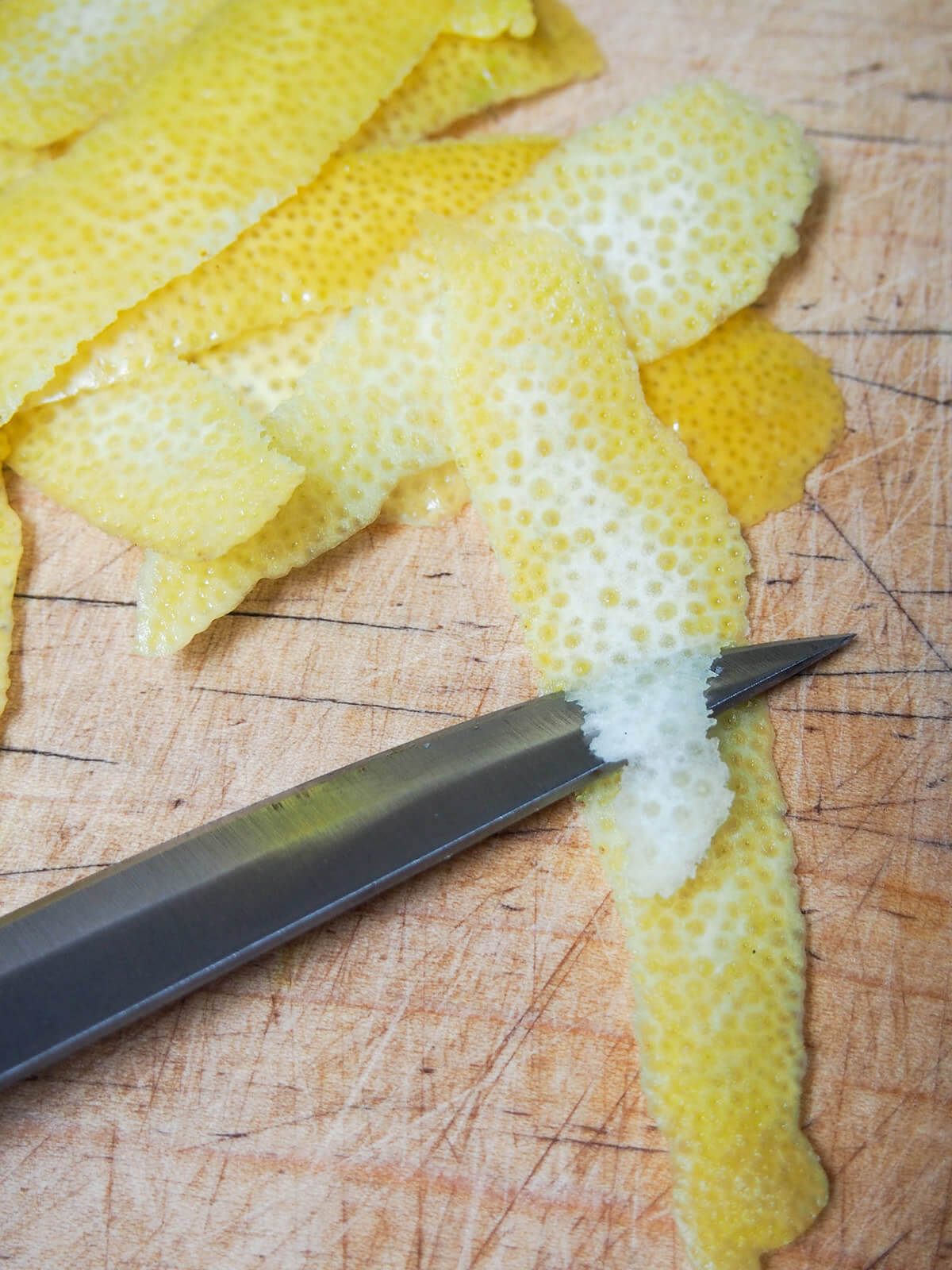 removing white pith from slices of lemon zest