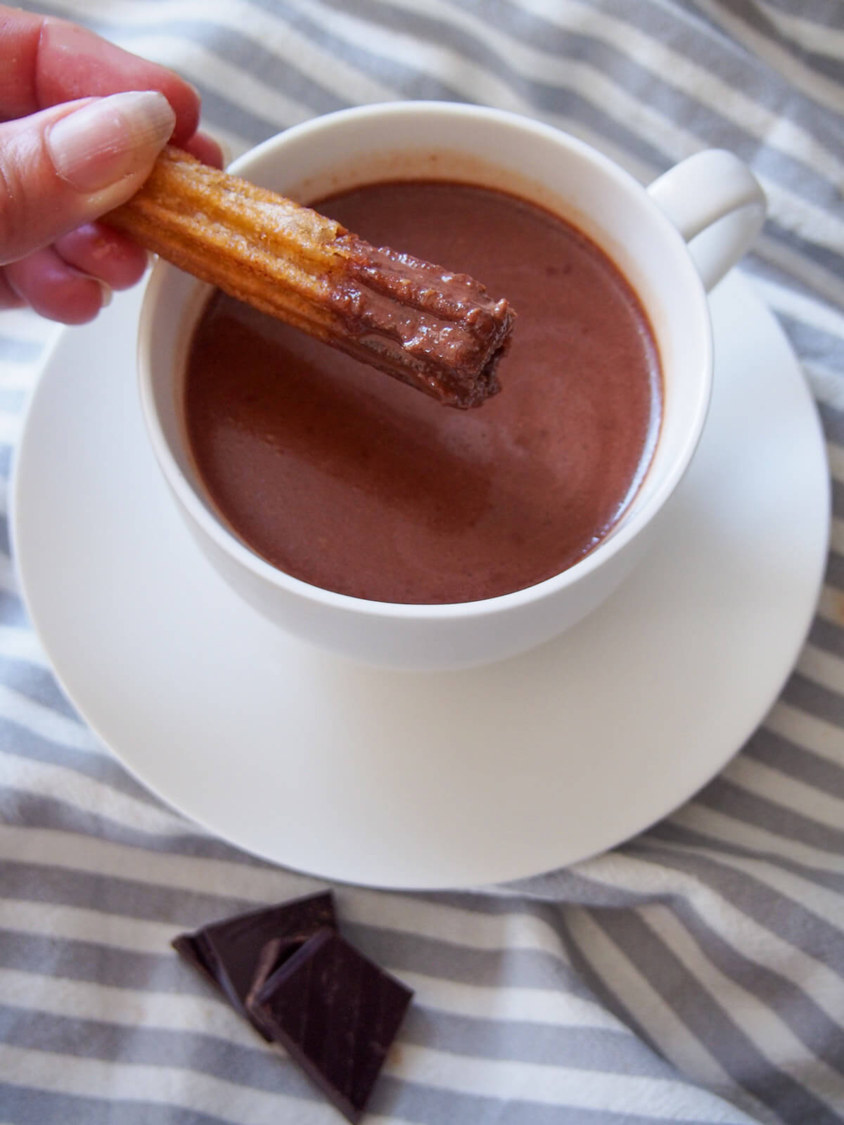 dipping churro into cup of hot chocolate