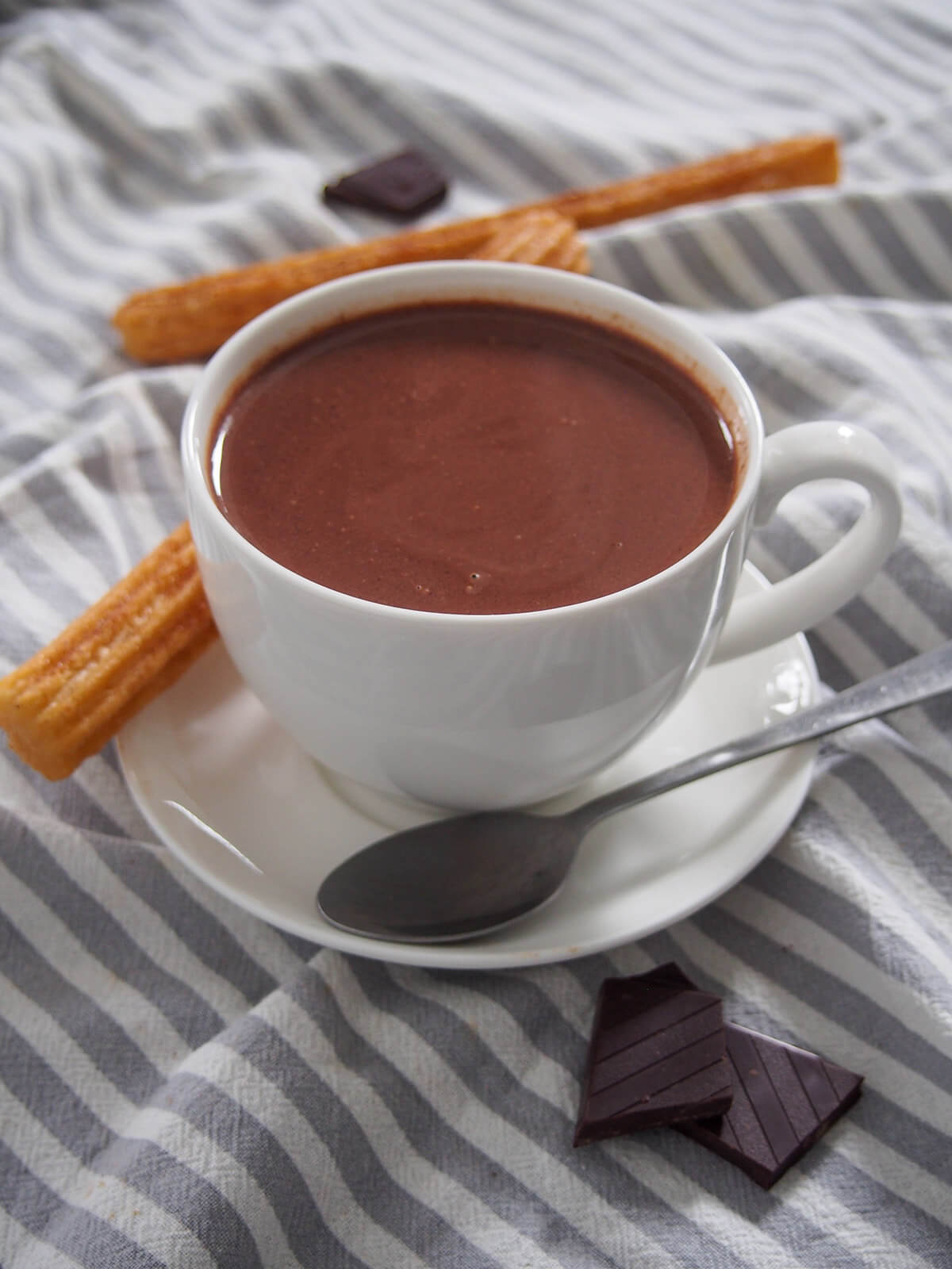 cup of Spanish hot chocolate with churros behind