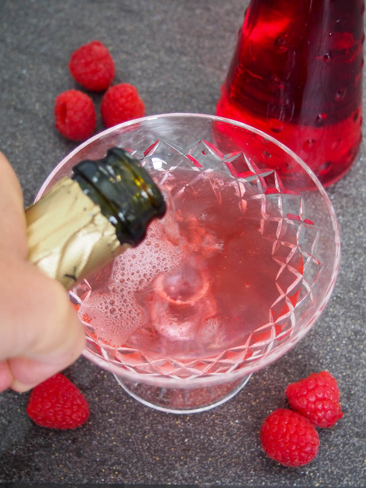 adding champagne to glass for kir imperial