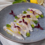 plate of fish crudo decorated with microgreens and mint