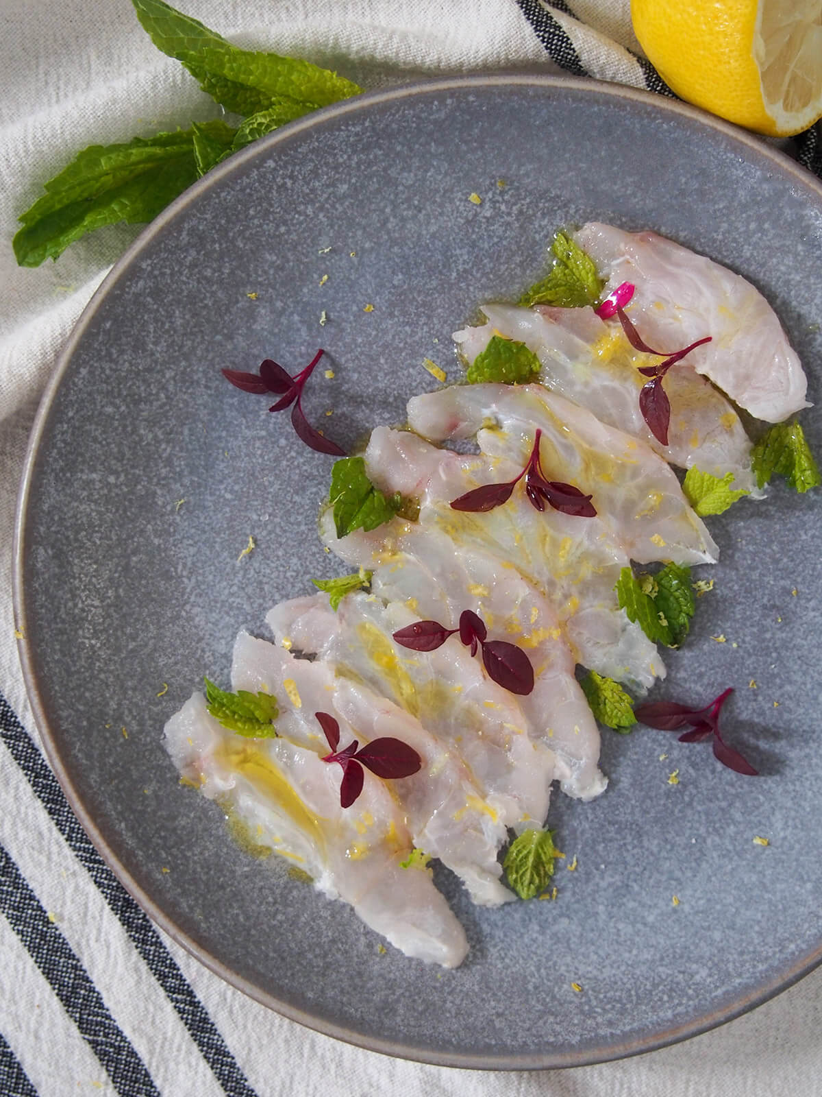 Fish crudo is a simple Italian preparation of raw fish. With only a few ingredients, it takes no time to prepare, but the result is elegant & delicious. plate of fish crudo from overhead