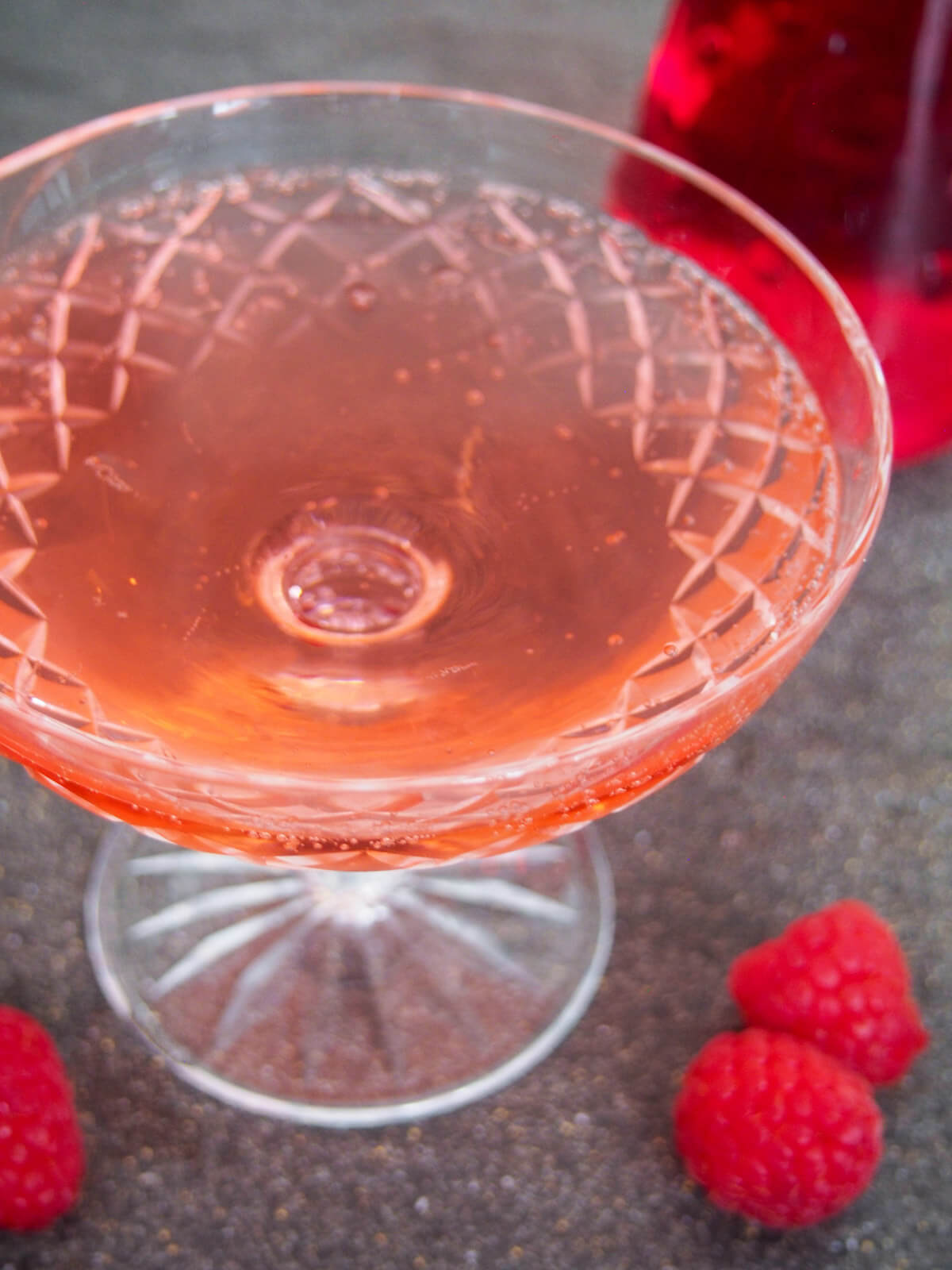 side view of glass kir imperial raspberry champagne cocktail