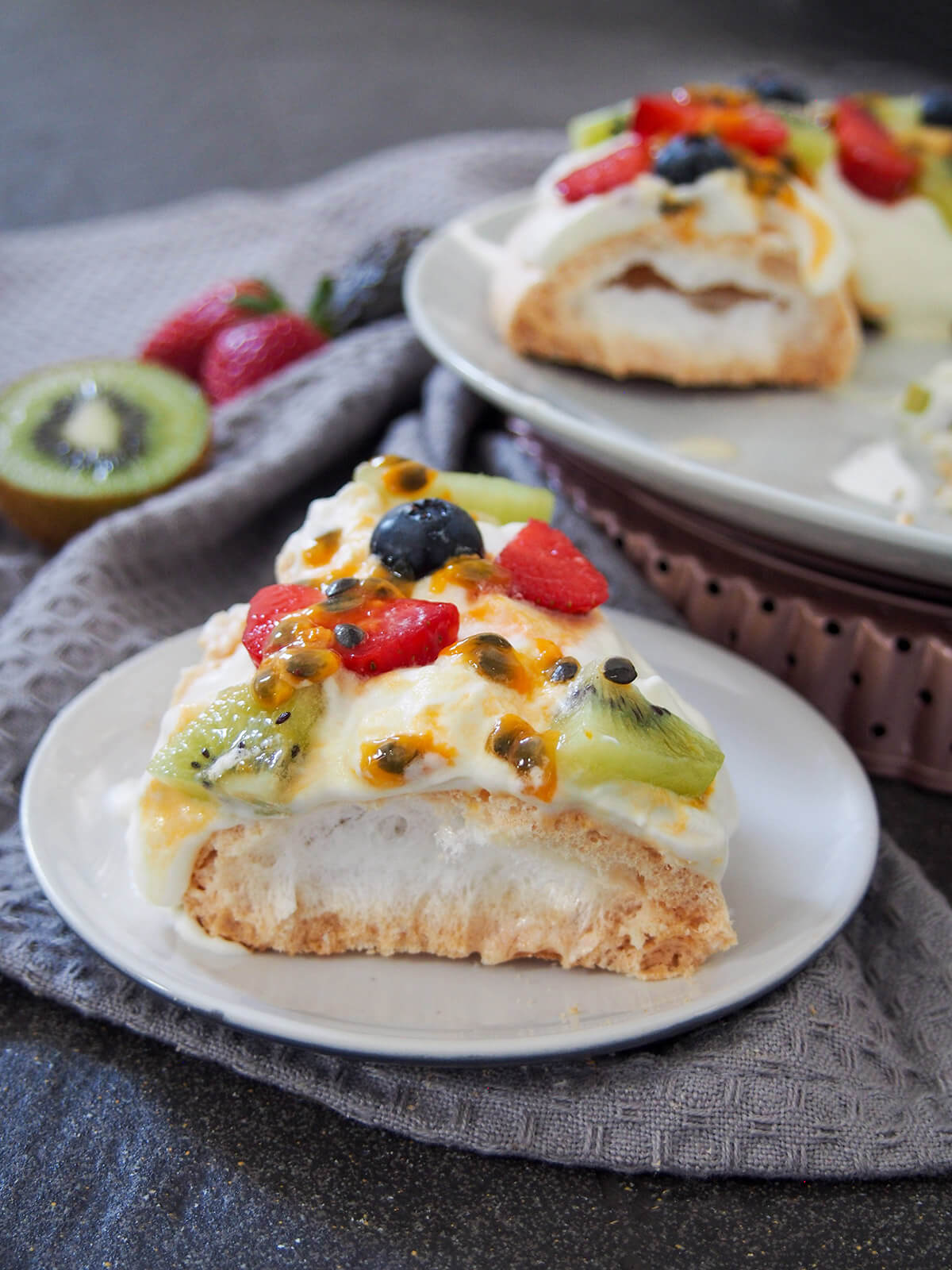 slice of pavlova wreath on small plate in front of rest