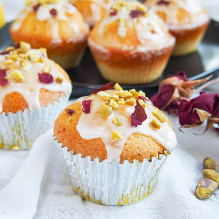 Persian love cake cupcakes with one to front with light frosting and pistachio rose decoration