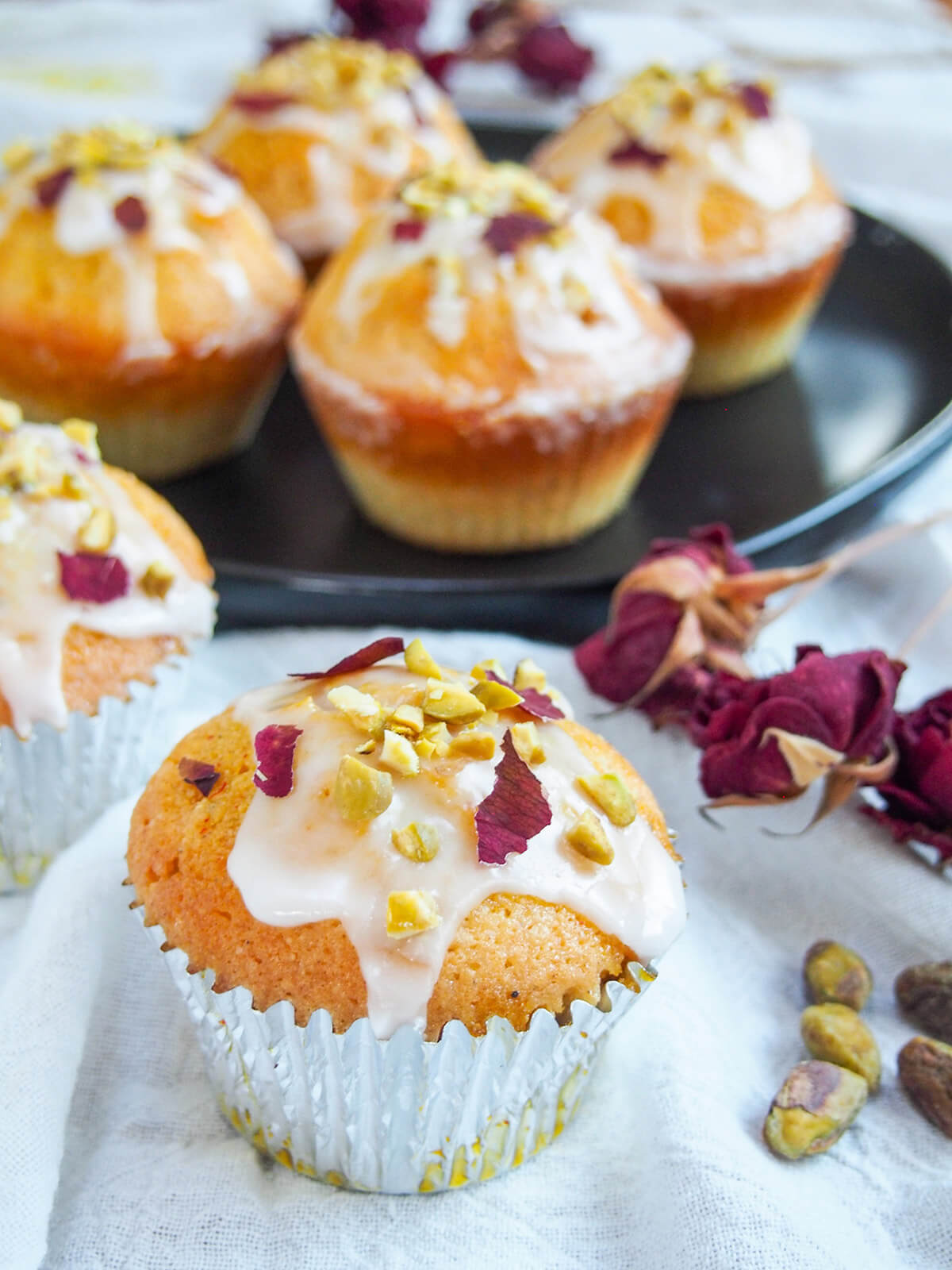 Persian love cake cupcakes with some on plate behind and one to front in silver casing