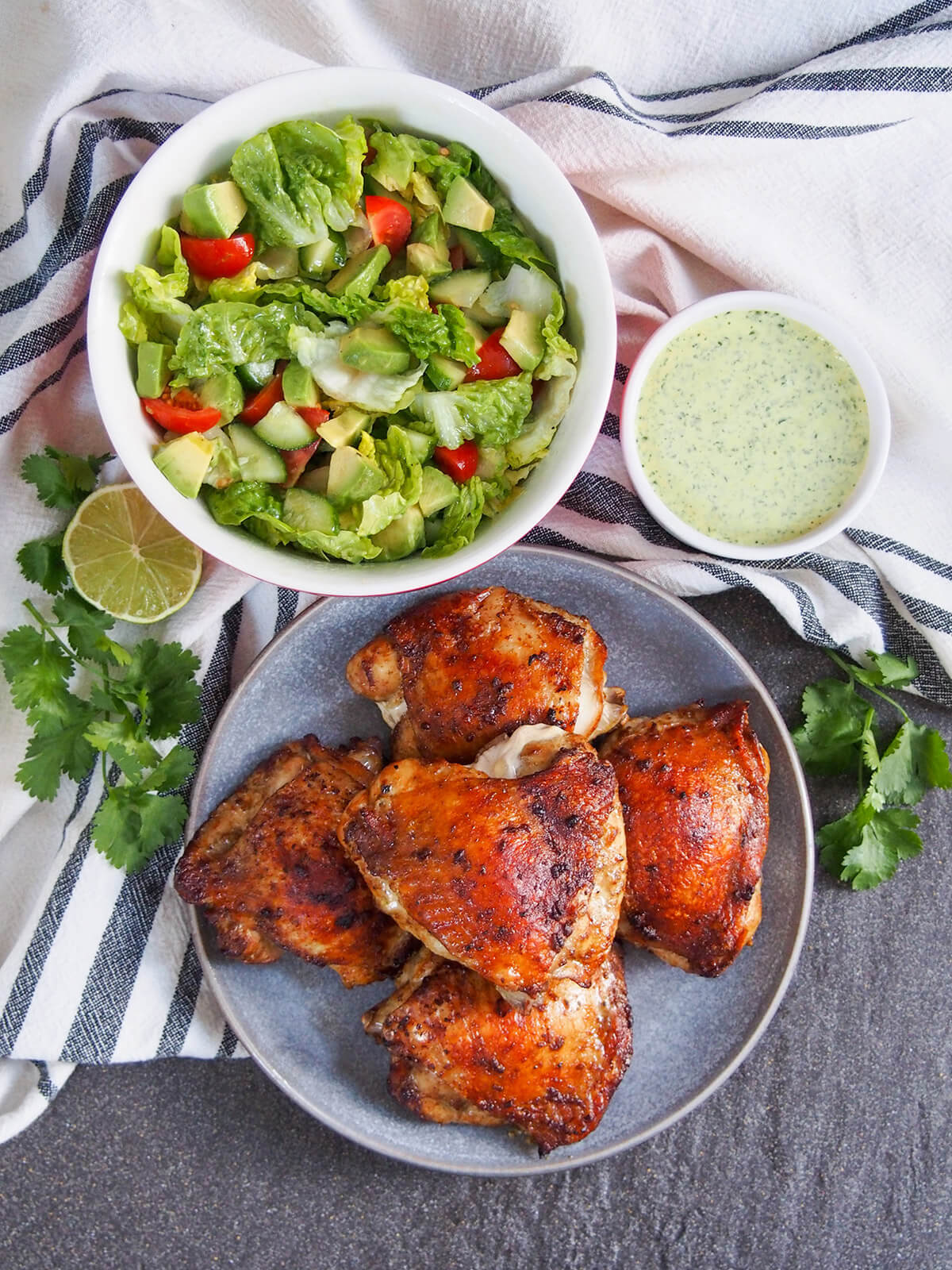 Peruvian roast chicken is traditionally made with whole chickens on a spit, but you can recreate the deliciousness with your oven. A simple but flavorful marinade adds an extra layer of flavor. plate with Peruvian roast chicken with sauce to side and bowl of salad viewed from overhead
