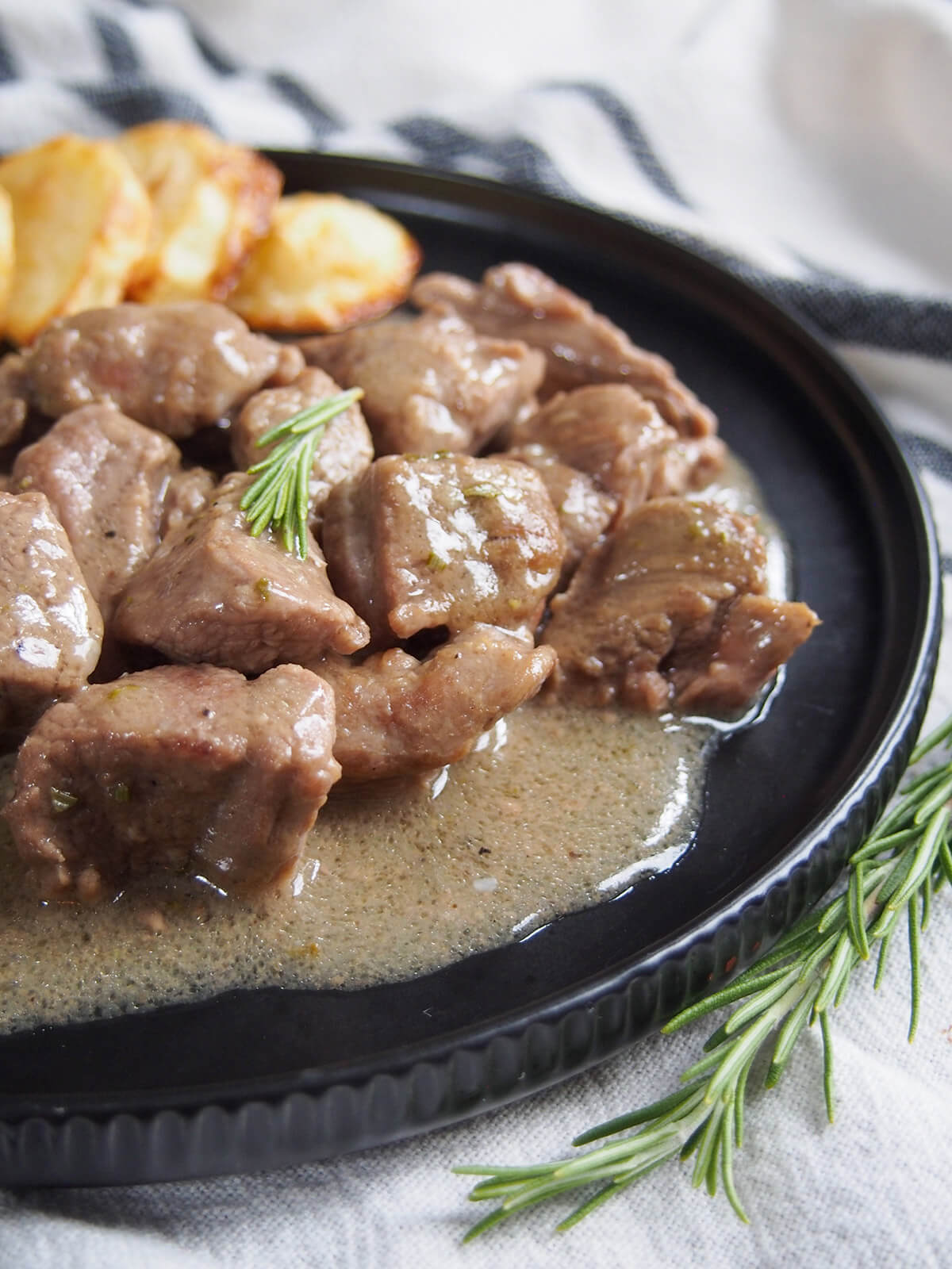 This traditional Roman lamb stew, abbacchio alla cacciatora, uses a relatively simple combination of ingredients including rosemary, garlic and vinegar to create a wonderfully comforting and flavorful dish. Easy and delicious. close up view of Roman lamb stew - abbacchio alla cacciatora