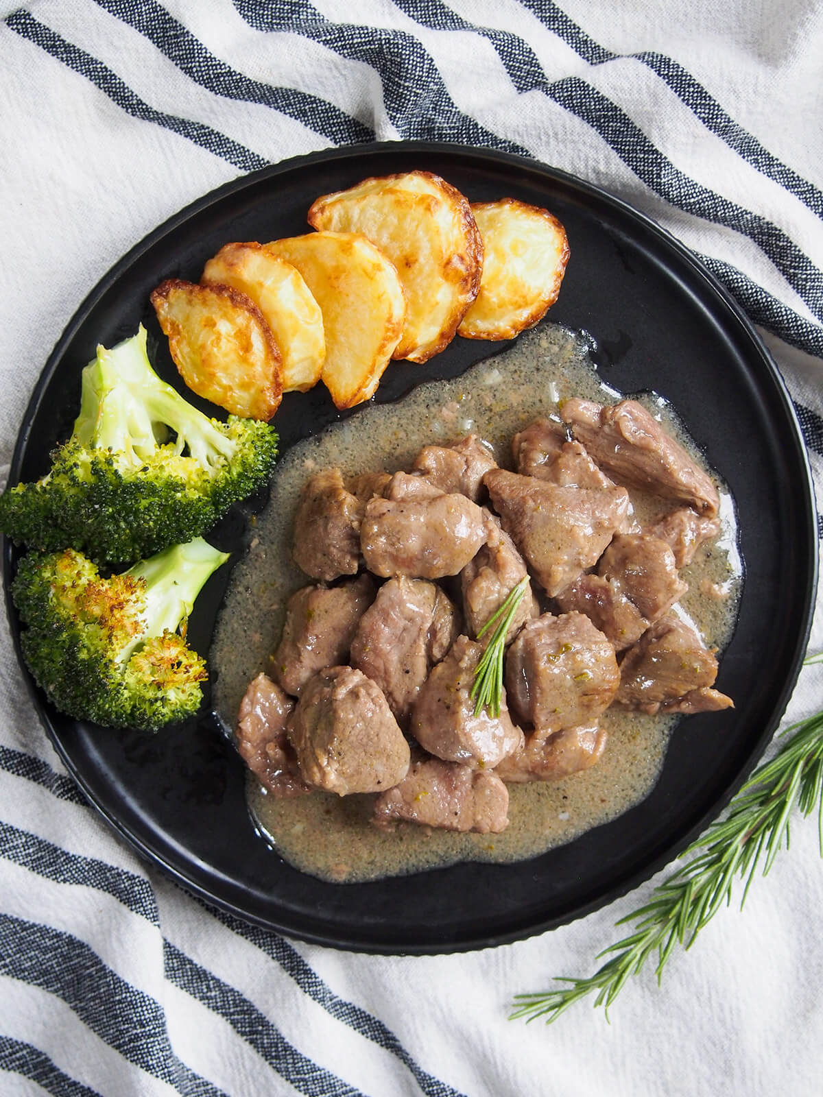 This traditional Roman lamb stew, abbacchio alla cacciatora, uses a relatively simple combination of ingredients including rosemary, garlic and vinegar to create a wonderfully comforting and flavorful dish. Easy and delicious. plate with Roman lamb stew, rosemary and potatoes form overhead