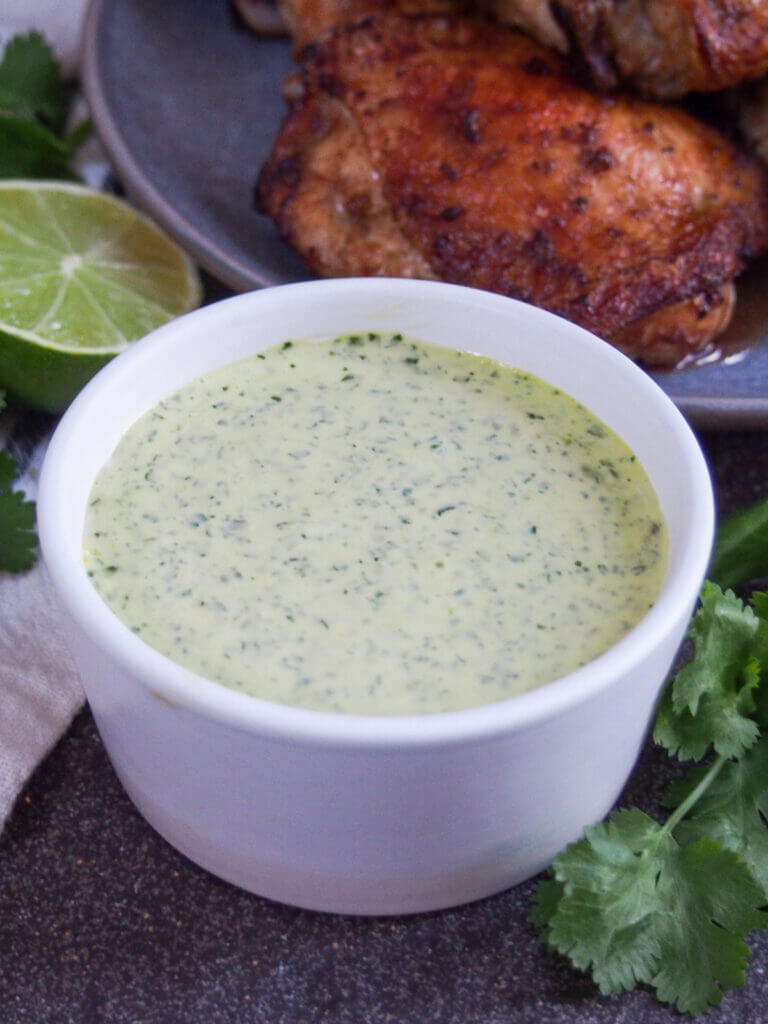 Aji verde, often called Peruvian green sauce elsewhere, is wonderfully easy and flavorful. It gets it's color from cilantro and has a little kick from aji amarillo, a popular Peruvian chili. So good. bowl of aji verde Peruvian green sauce with chicken behind