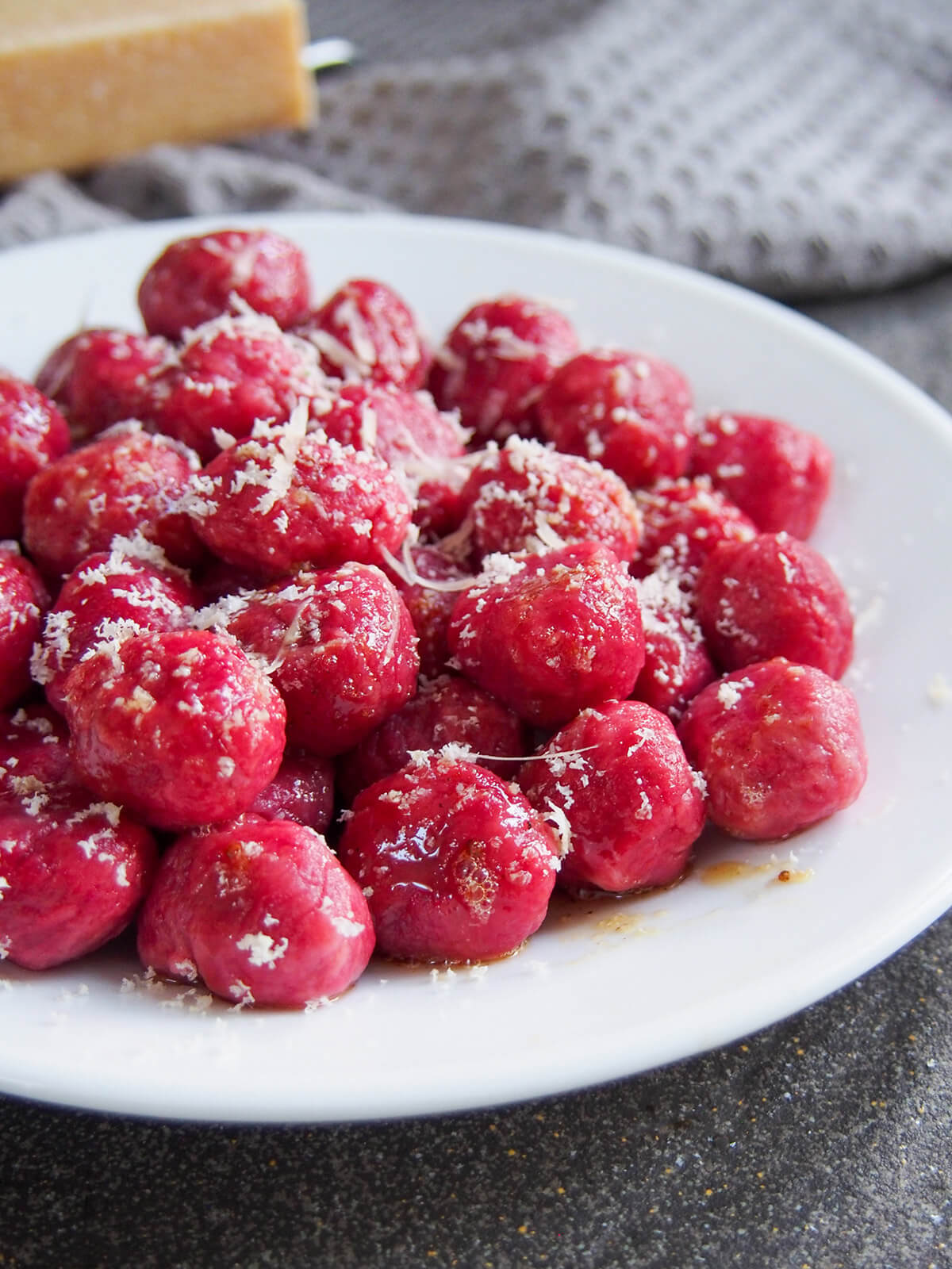 beet gnocchi on plate with cheese behind