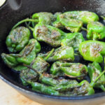 skillet with blistered Padron peppers