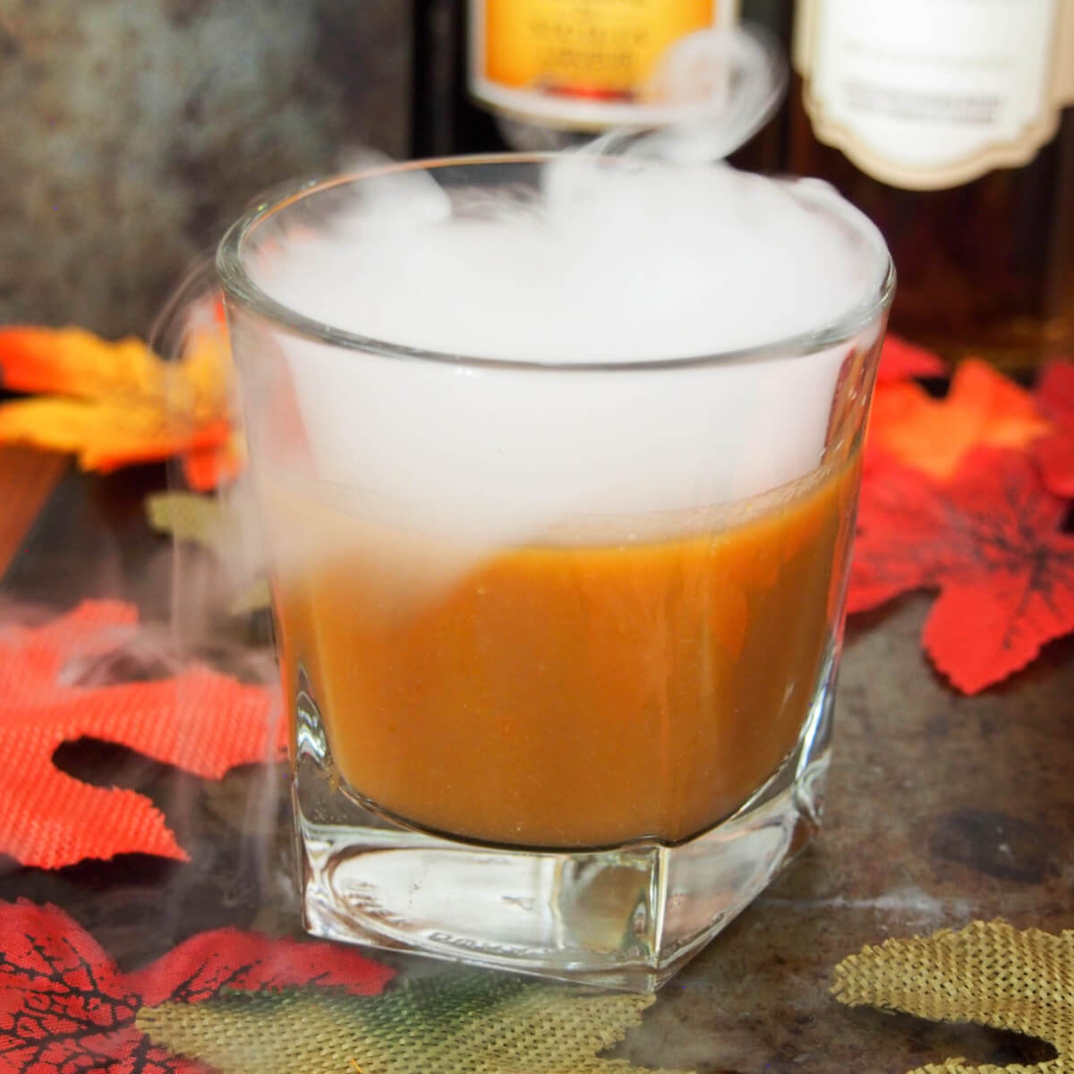 Falling for orange: amaro pumpkin cocktail with bottles behind