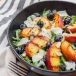 grilled peach salad in bowl from side with fork in front