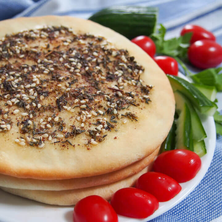 Manakish on plate with tomatoes and cucumber to side