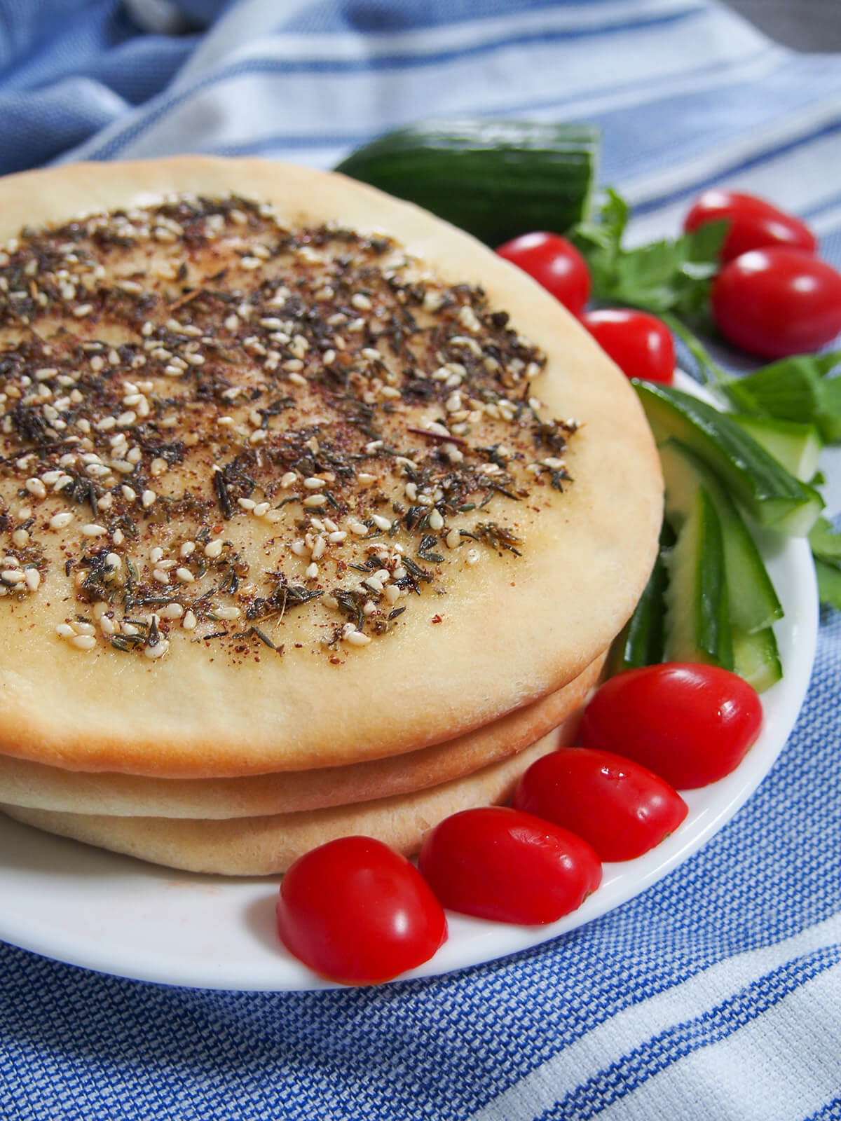 stack of Manakish Lebanese za'atar flatbread with tomatoes on edge of plate