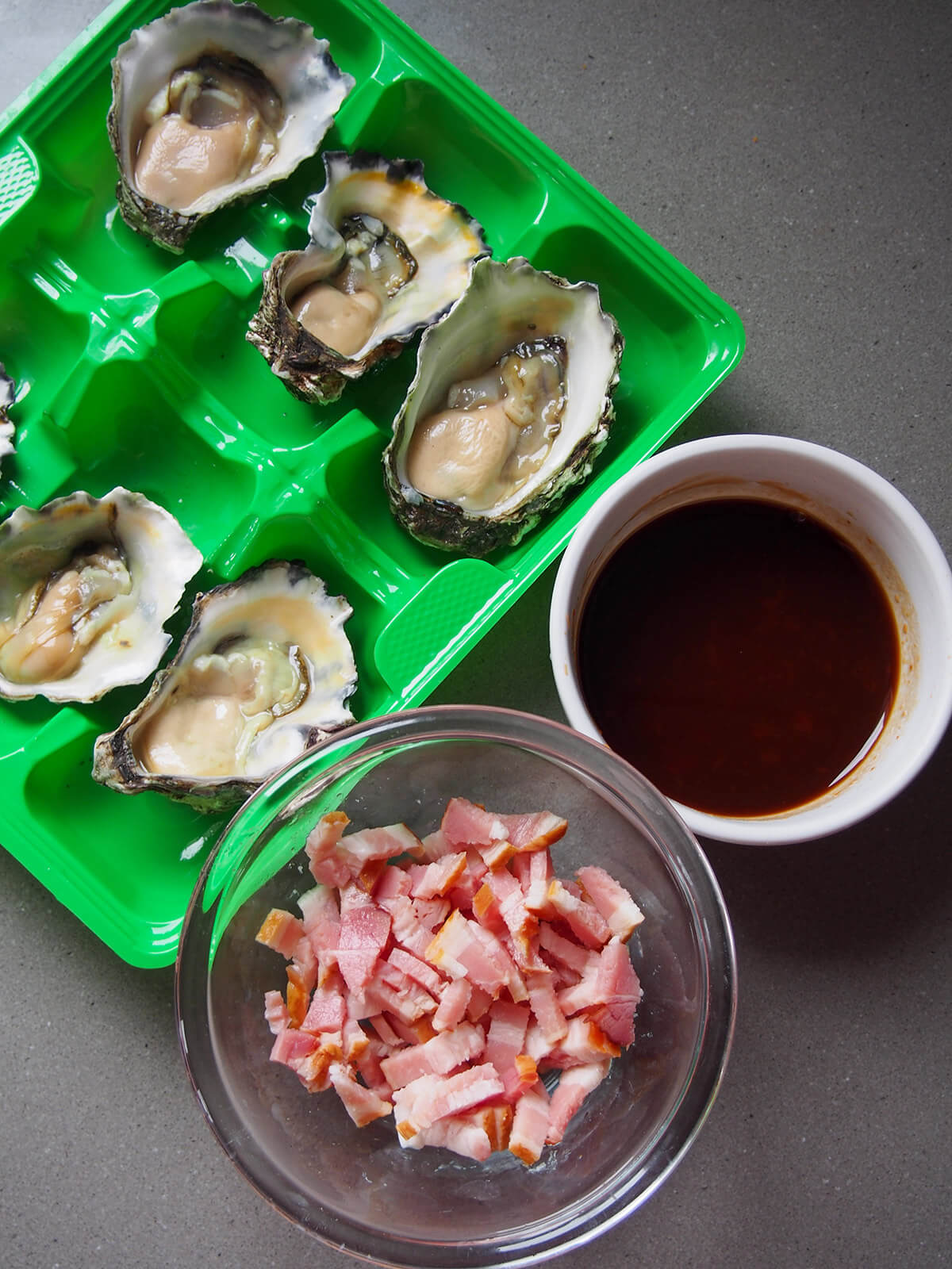 oysters, sauce and bacon pieces next to each other