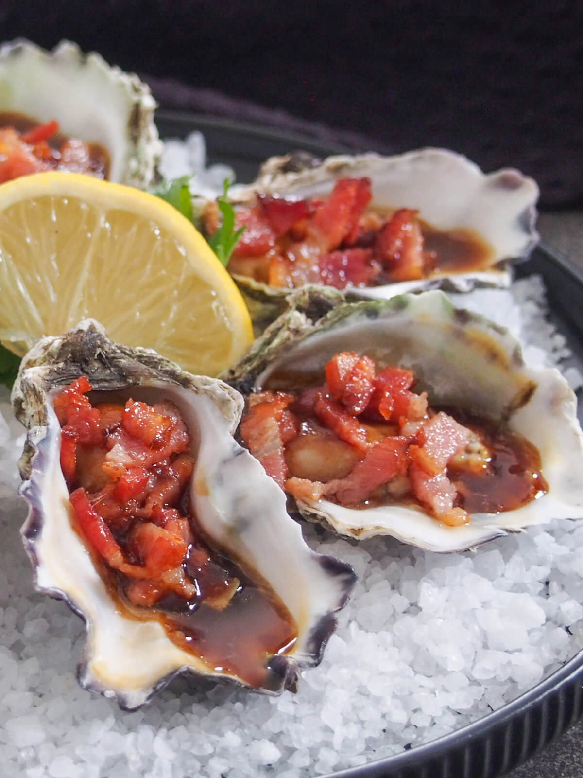 side view of oysters Kilpatrick on bed of rock salt