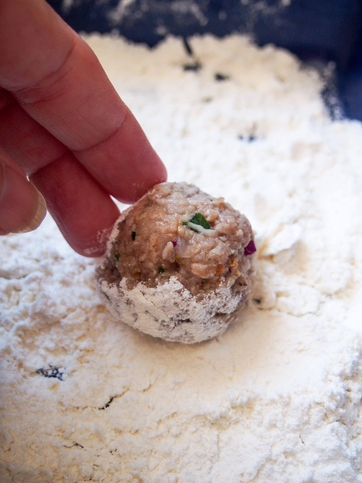 rolling a meatball in flour