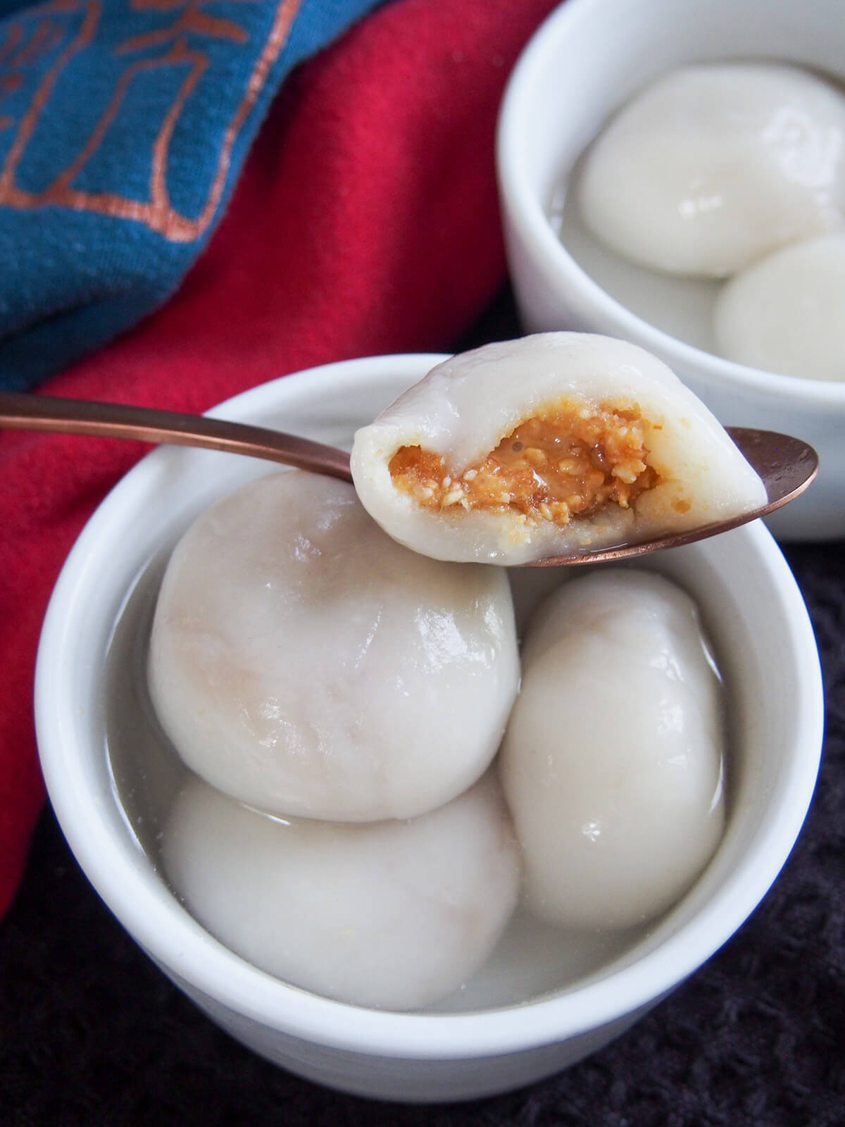 a bitten-open Chinese sweet dumpling showing filling resting on bowl with others