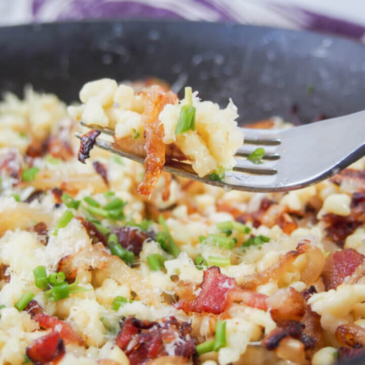 Bacon onion spaetzle with forkful held over rest