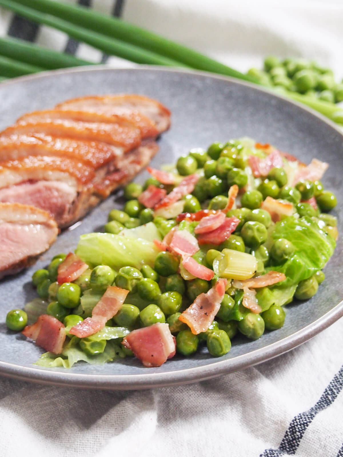 Petits pois a la francaise French peas on plate with sliced duck to side