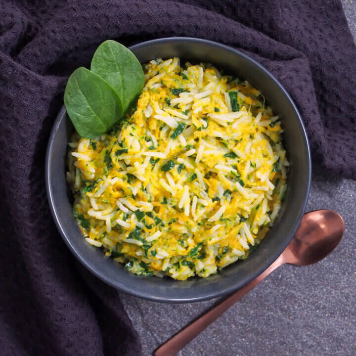 bowl of rice with vegetables and coconut milk with spoon to side