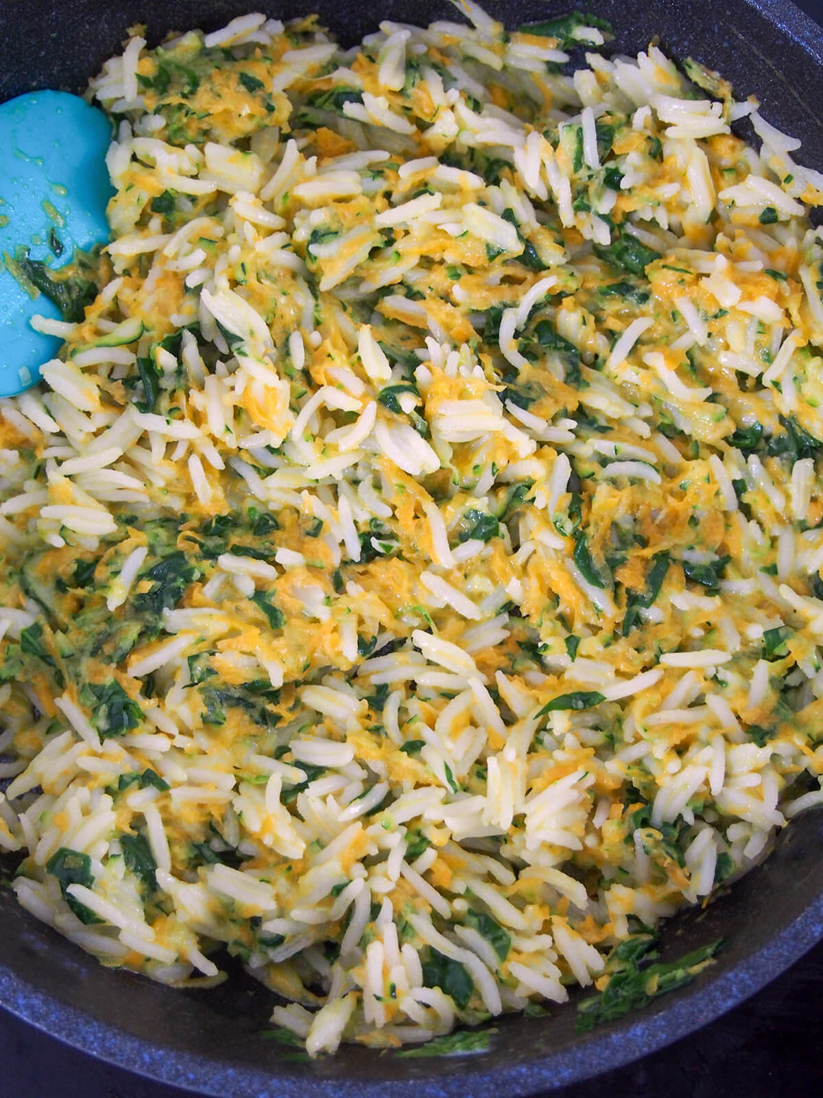 cooking rice with vegetables and coconut milk adding rice and coconut milk to softened vegetables in skillet