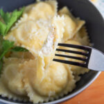 crab ravioli with one held on fork showing filling inside