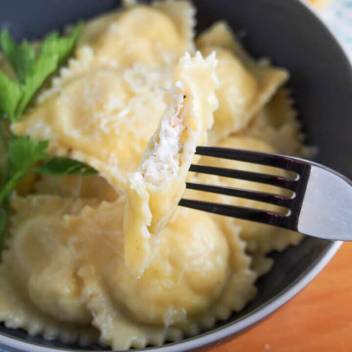crab ravioli with one held on fork showing filling inside