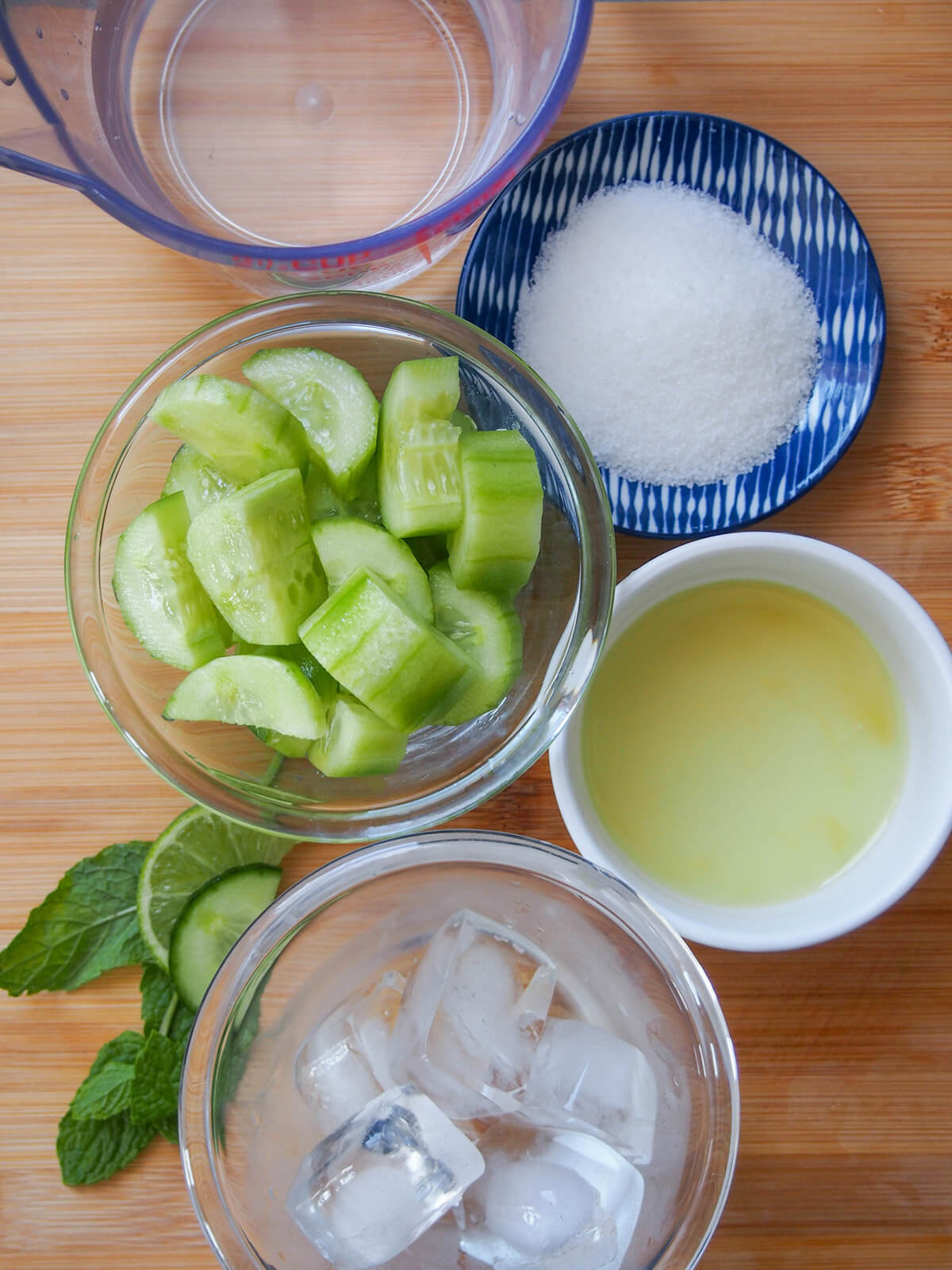 dishes with cucumber, ice, water, lime, sugar and mint to side
