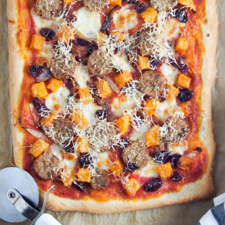 fall pizza with squash and sausage with cutter to side