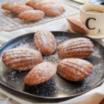 plate of gingerbread madeleines with more on rack behind
