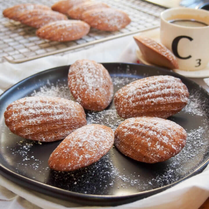 plate of gingerbread madeleines with more on rack behind