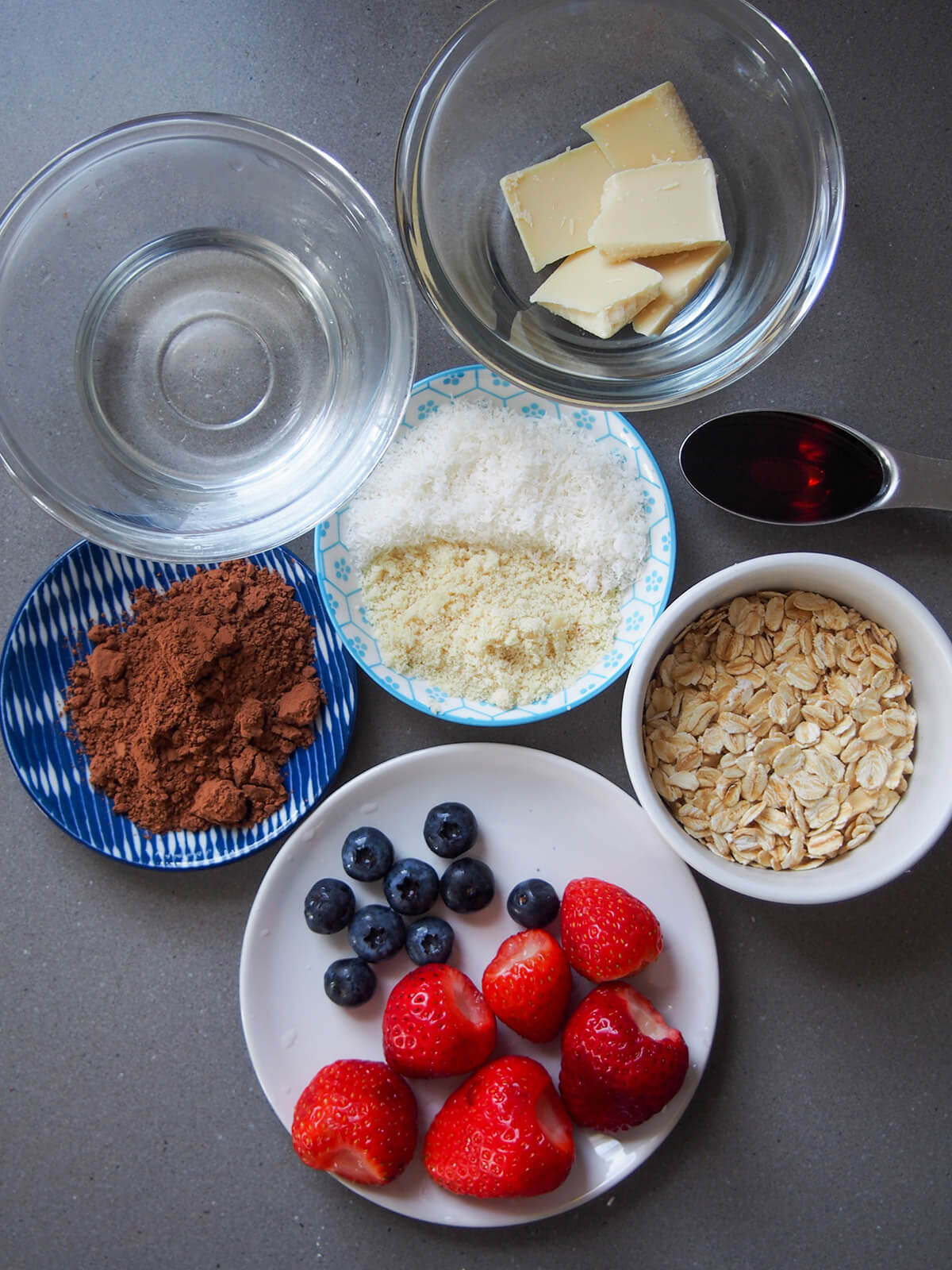 bowls with ingredients - oats, coconut oil, cocoa powder, white chocolate and fruit