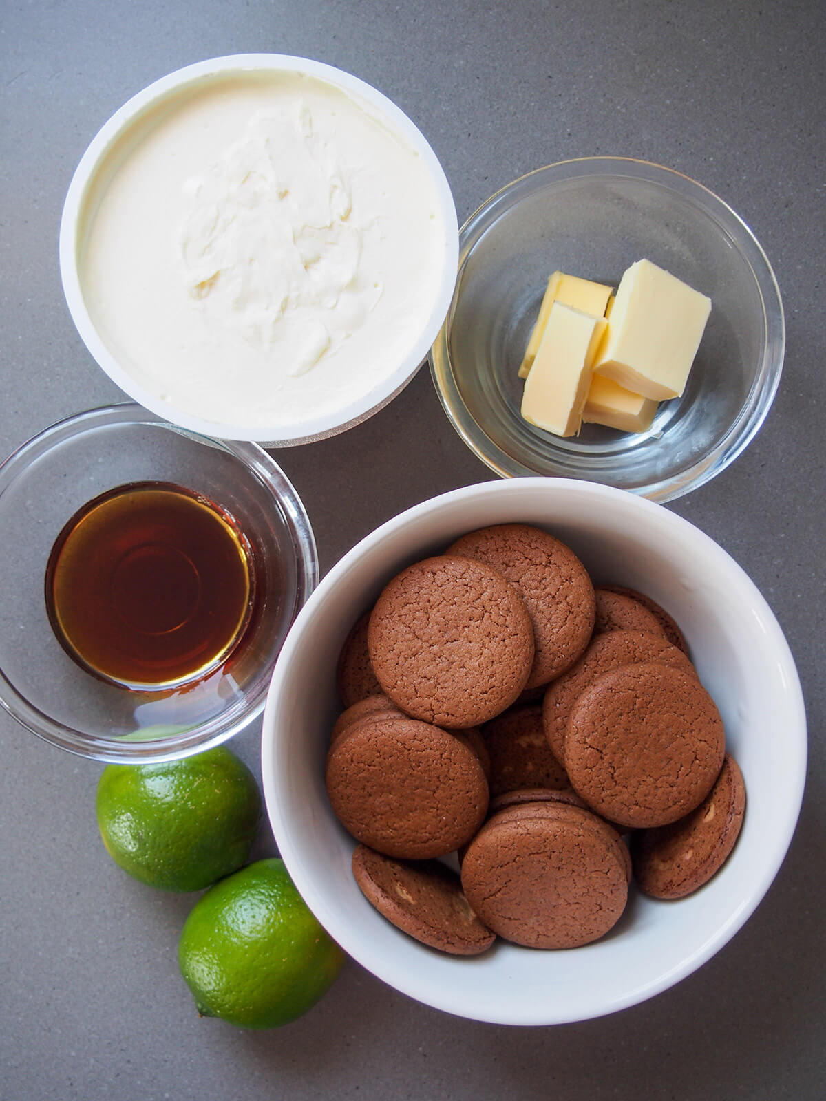 ingredients in separate bowls (limes, mascarpone, ginger snaps, butter and maple syrup)