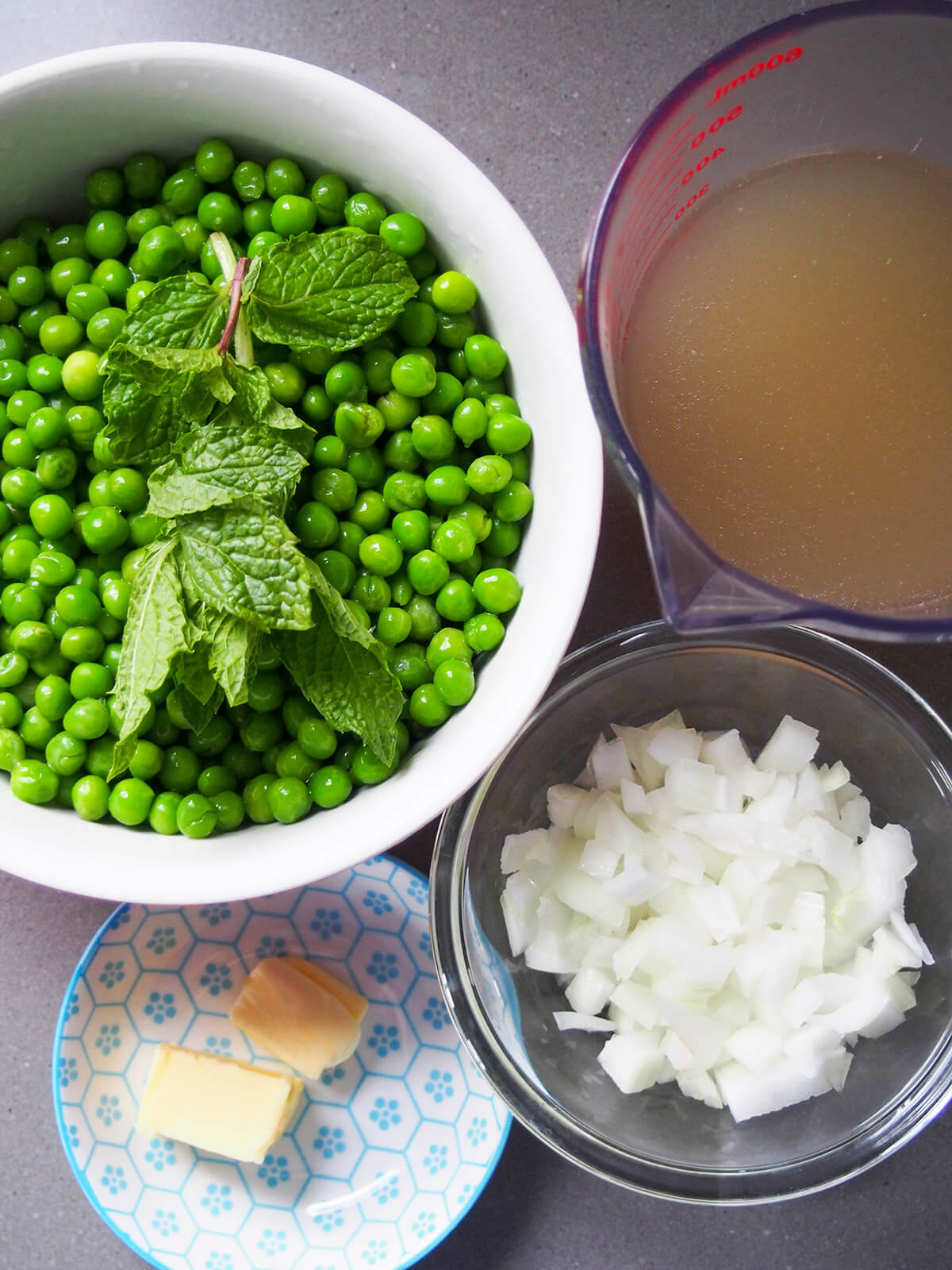bowl of peas with mint on top, stock, onions and butter