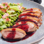 pan seared duck breast with blackberry sauce with peas to side
