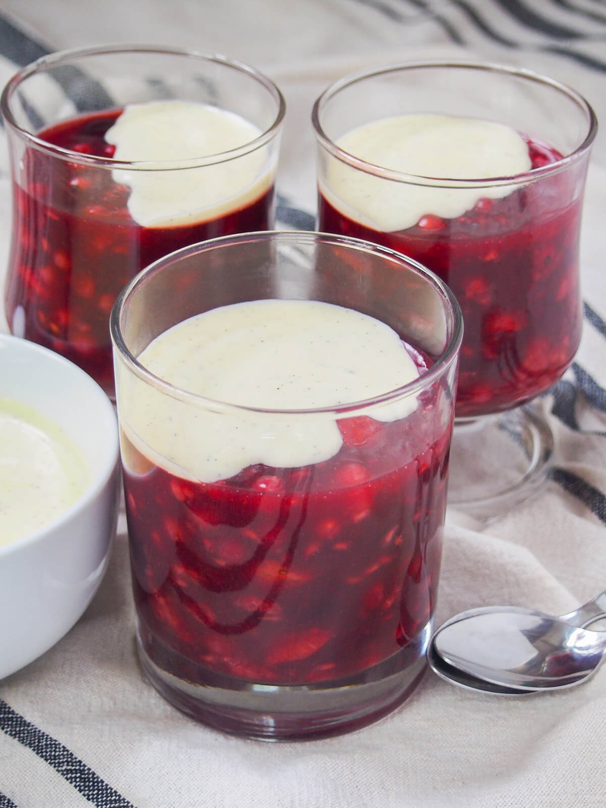 glasses of Rote Grütze (Rote Gruetze) with some vanilla sauce on top of mixture