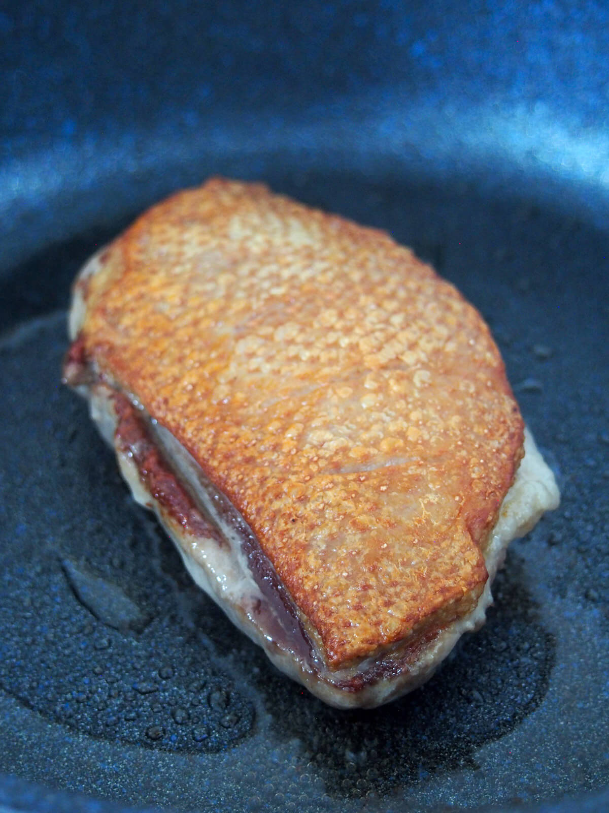 searing duck breast in skillet with crisp skin on top