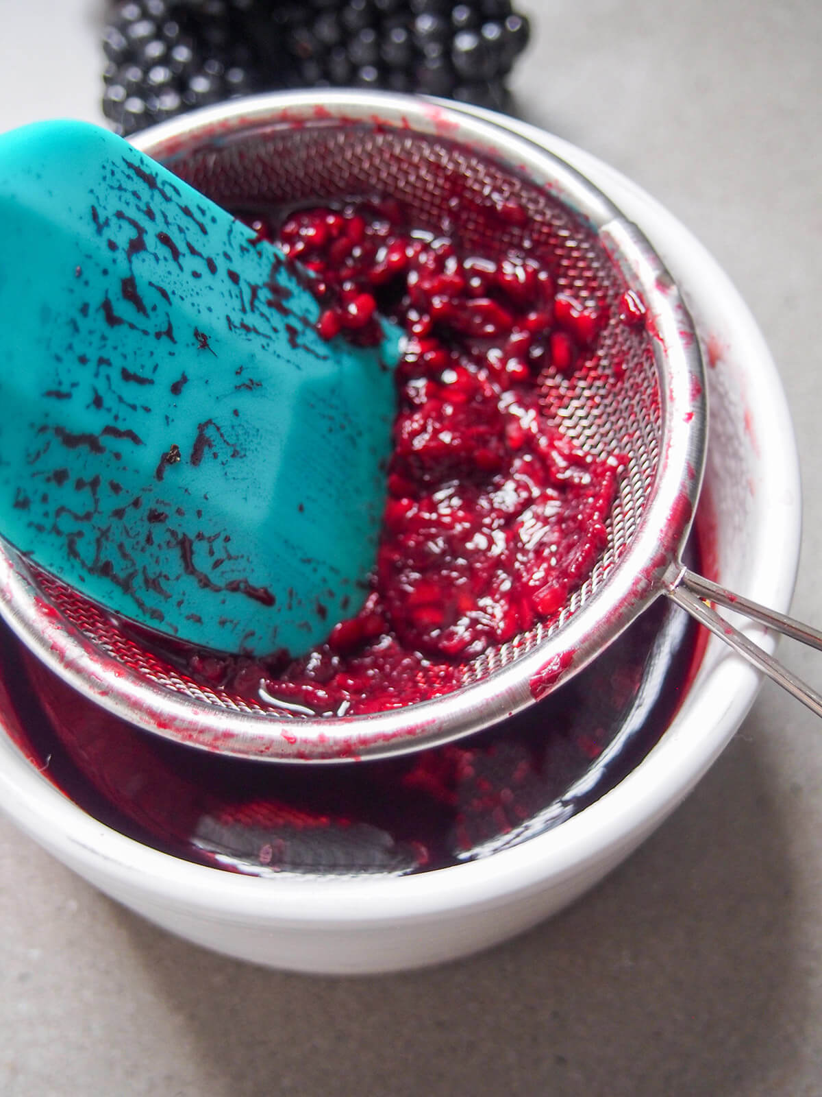 pressing blackberry sauce through strainer