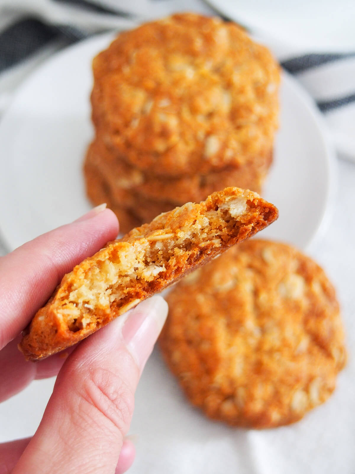 holding bitten biscuit in front showing texture inside with blurred stack behind