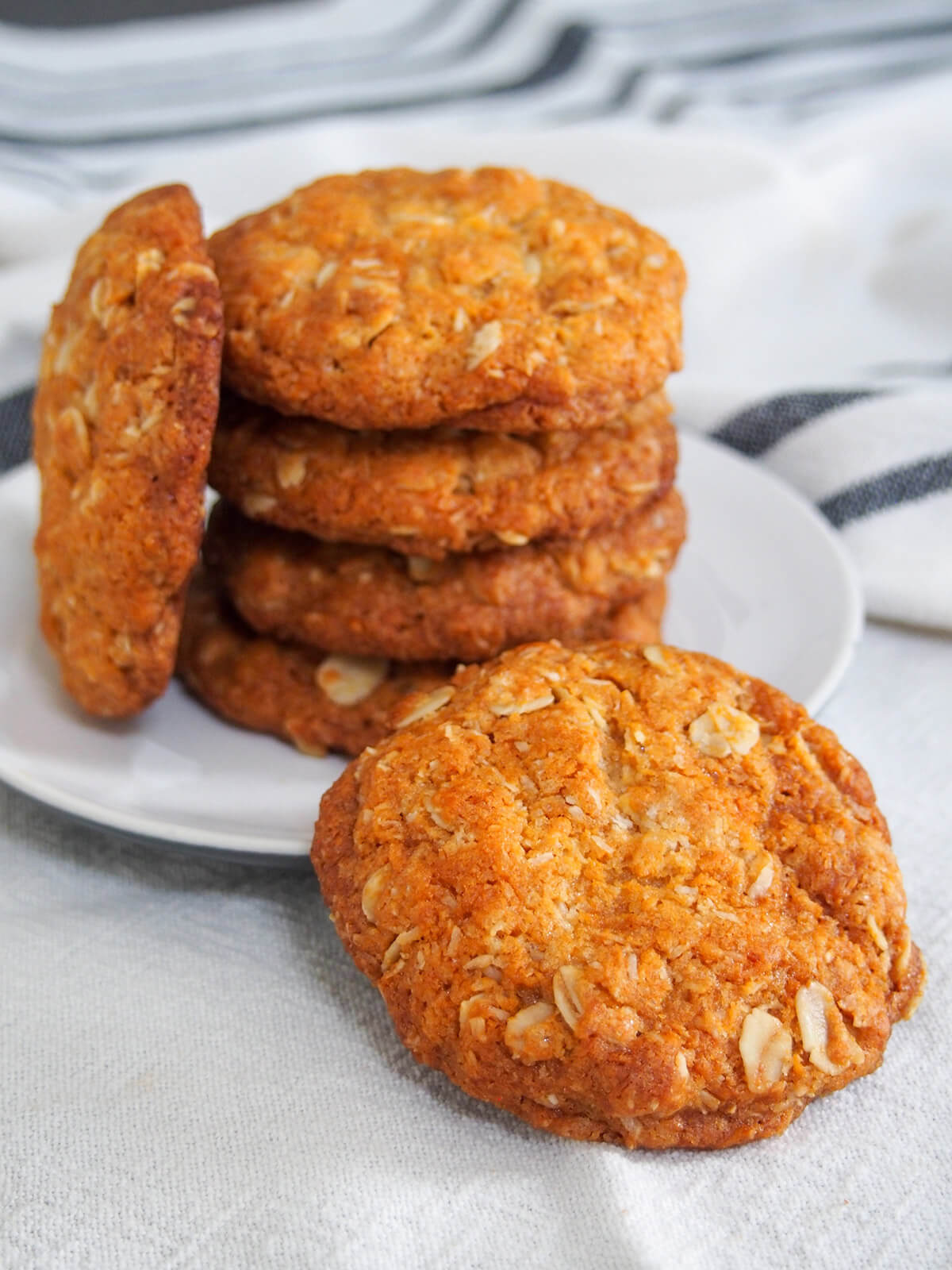 stack of Anzac biscuits with one in front resting on plate