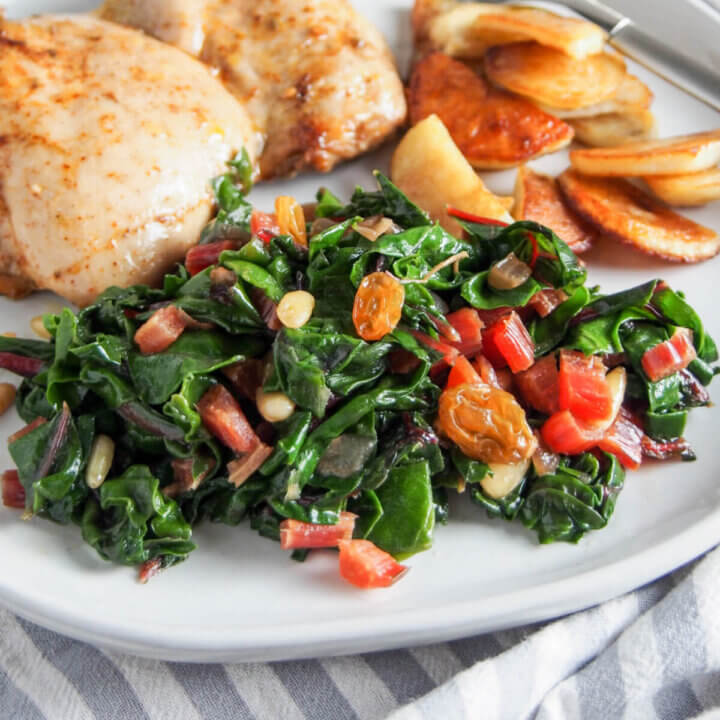Catalan style sauteed Swiss chard in front of chicken and potatoes on plate