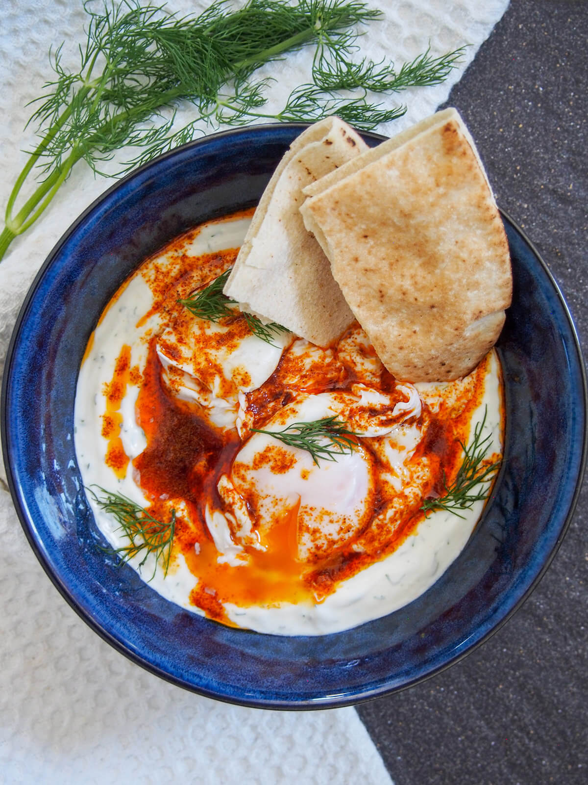 bowl of Turkish eggs cilbir with pieces of pita in bowl